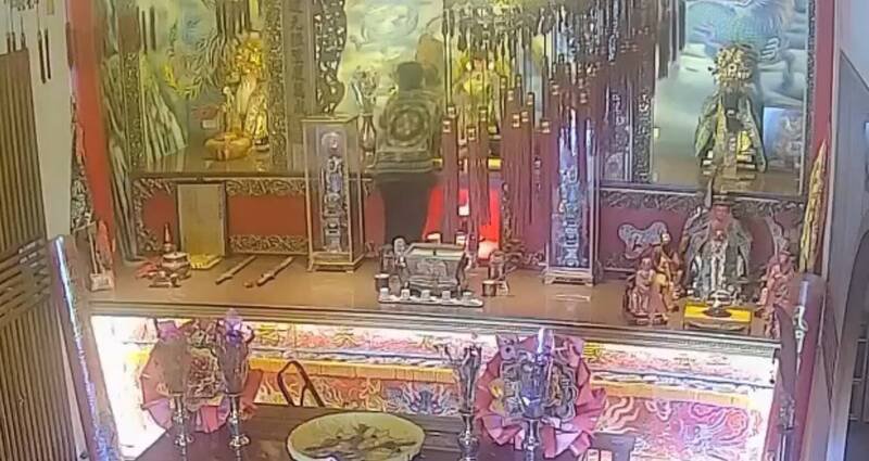罗嫌顺著供桌爬上,伸手取下金牌并塞进衣中。(记者刘人玮翻摄) 罗嫌顺著供桌爬上,伸手取下金牌并塞进衣中。(记者刘人玮翻摄)