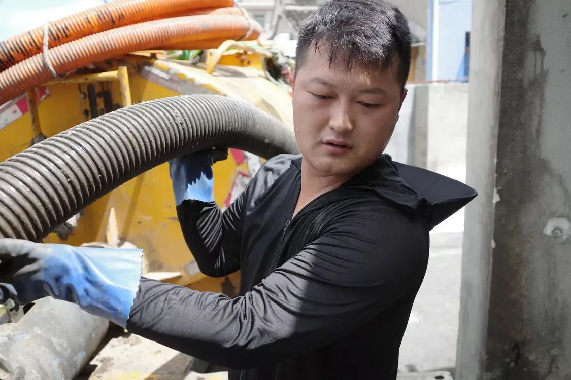 ▲工作时，潘浩男需要拖着几十公斤重的抽粪管 红星新闻记者 付垚 摄