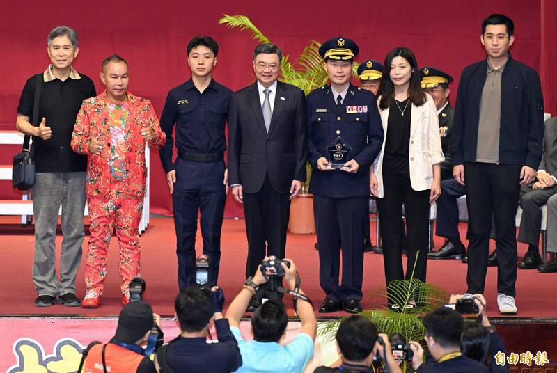 行政院长卓荣泰(中)22日出席台湾警察专科学校庆祝80周年校庆大会,颁奖给杰出校友时,竹北「吊车大王」胡汉䶮(左二)以获奖人亲友身分上台合影,引起全场瞩目。(记者廖振辉摄) 行政院长卓荣泰(中)22日出席台湾警察专科学校庆祝80周年校庆大会,颁奖给杰出校友时,竹北「吊车大王」胡汉䶮(左二)以获奖人亲友身分上台合影,引起全场瞩目。(记者廖振辉摄)