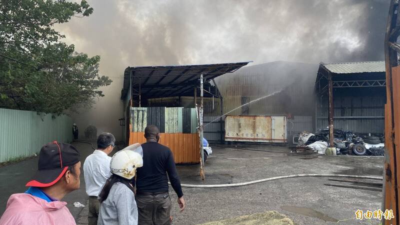 桃园区树仁三街网拍仓库火灾有扩散到后方废车辆与废轮胎回收场之虞,消防单位增设水线降温隔热,回收场奈及利亚裔张姓男负责人(黑衣者)很是焦急。(记者陈璟民摄) 桃园区树仁三街网拍仓库火灾有扩散到后方废车辆与废轮胎回收场之虞,消防单位增设水线降温隔热,回收场奈及利亚裔张姓男负责人(黑衣者)很是焦急。(记者陈璟民摄)