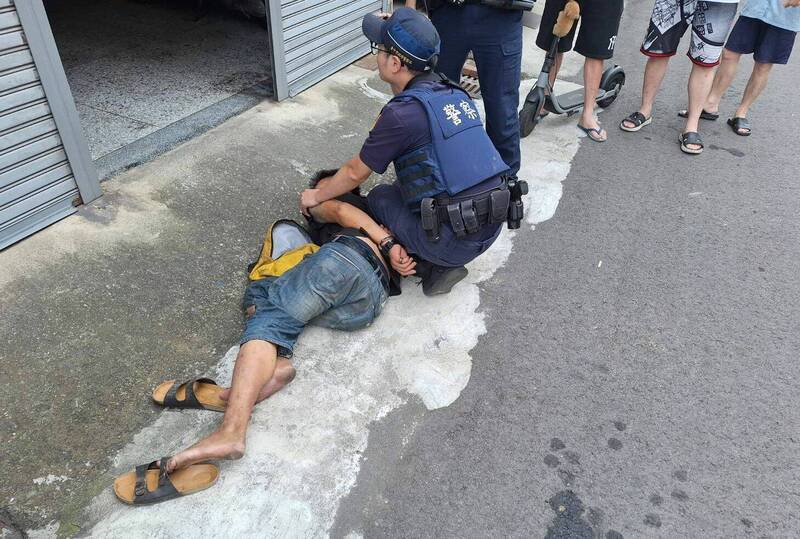 台中庄姓男子，今天上午在大里乔城路持铁棒沿路砸车，警方获报到场将他压制。（记者陈建志翻摄）