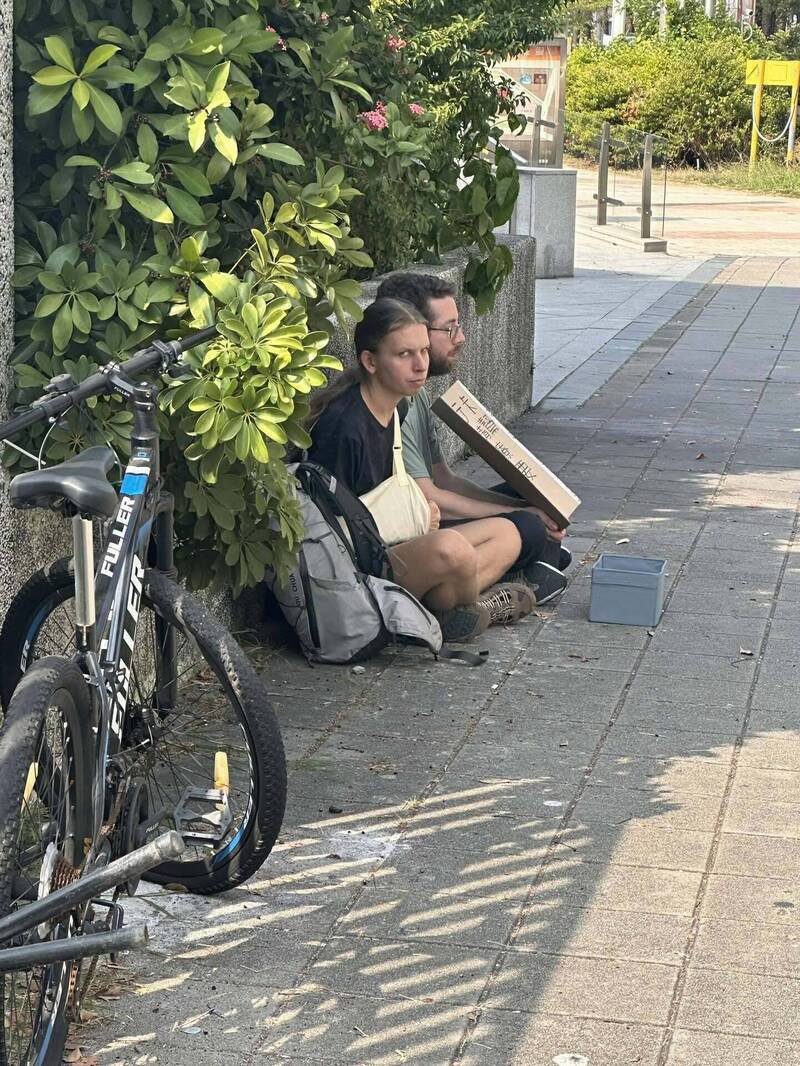 2名外籍男子在高雄巨蛋附近，持纸板向路人乞讨。（撷取自threads@pudding14221）