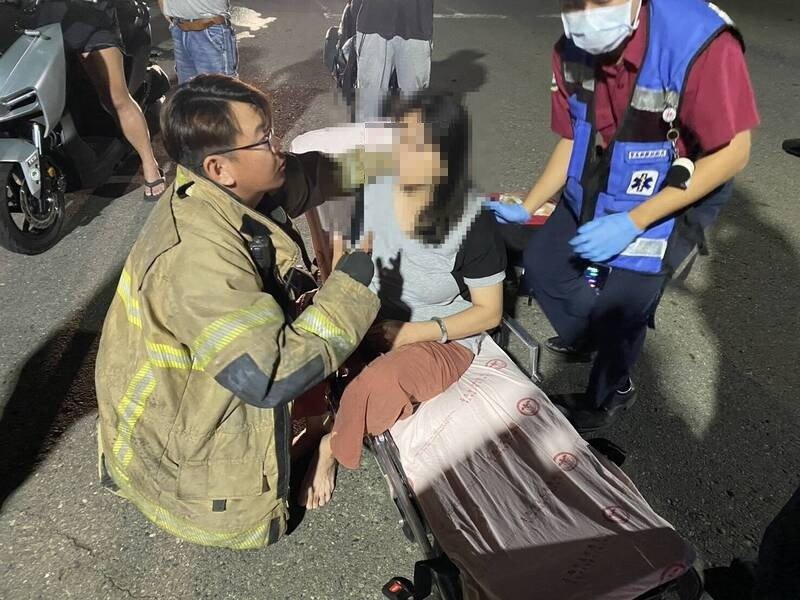 女驾驶自行爬出车外获救，消防员检伤。（民众提供）