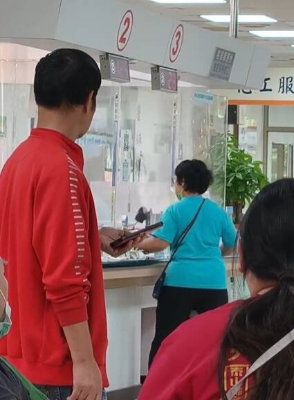 蓝衣妇人在医院柜台乱挥手弄坏显示器等物品。（撷取自网路）