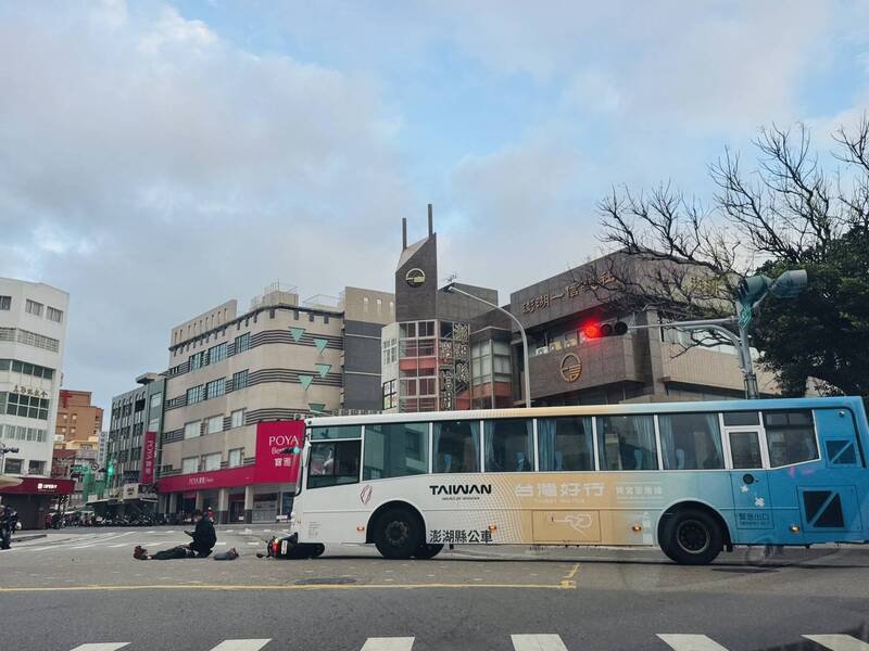 机车骑士车祸倒地，公车司机守候在旁并拨电话报警。（民众提供）