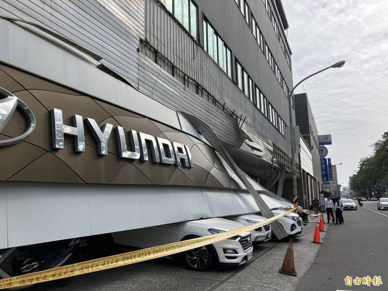 进口车商门市约30米宽的巨型招牌突然崩落，直接砸中下方停放的9部汽机车。（记者蔡清华摄）