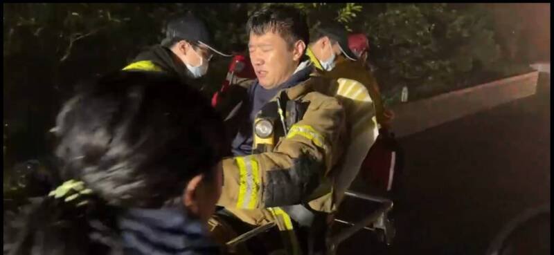 基隆市安乐分队小队长杨祥义搜救受困詹能杰时，右手肘触电后，双脚痛麻，被同仁抬出火场。（记者林嘉东翻摄）
