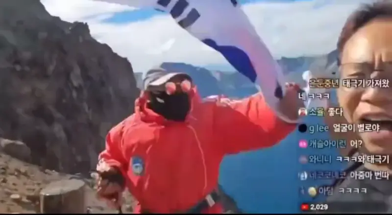 ▲韓國一名網紅日前到中國東北旅遊，在登上長白山時，拿出韓國國旗揮舞還唱韓國國歌，隨即一旁工作人員就沖上前搶走國旗。（圖／翻攝自微博）