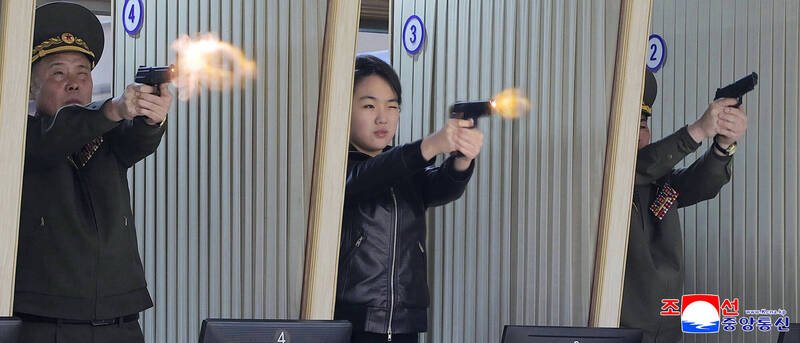 北韩领导人金正恩女儿金主爱（中）在军需工厂内试射新型手枪。分析指出，平壤当局释出这类开枪画面，意在持续为她塑造未来的军事接班领袖形象。（美联社）